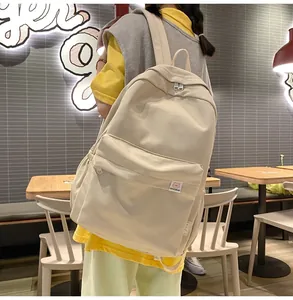 Detail view of a beige high-capacity school backpack with a cute cartoon bear patch