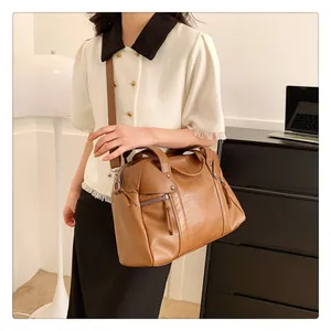 Brown leather tote handbag with double zipper details shown in a lifestyle office setting
