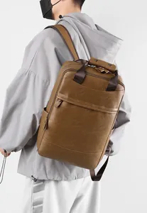 Détail du sac à dos en cuir marron avec poignées porté par un mannequin homme de dos