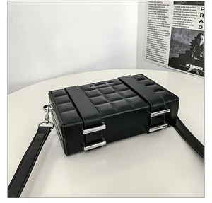 Macro detail of black quilted box bag with silver buckles and adjustable leather strap