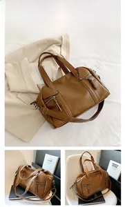 Detail of a brown PU leather Boston bag showing dual handles and adjustable shoulder strap