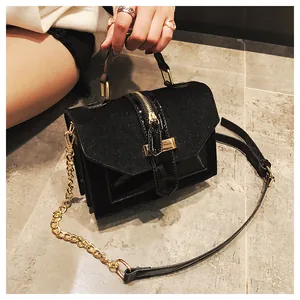 Detalle de bolso negro de cuero patchwork con cremallera dorada y correa de cadena