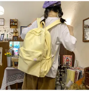 Detail view of a pale yellow canvas backpack showing the large front zip pocket and side pouch