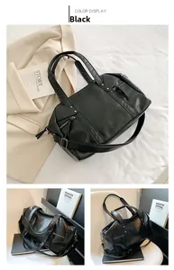 Detailed view of black leather tote bag with vertical zipper and adjustable shoulder strap