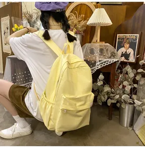 Detail view of the pale yellow canvas backpack featuring side pockets and a spacious main compartment