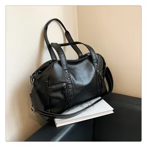 Detail of black PU leather bag with metallic rivets and decorative side zippers