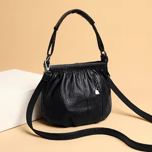 Sac à main froncé en cuir souple noir avec bandoulière et détail zippé frontal