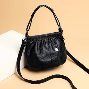 Sac bandoulière nuage noir avec texture plissée et breloque cœur argent sur fond beige