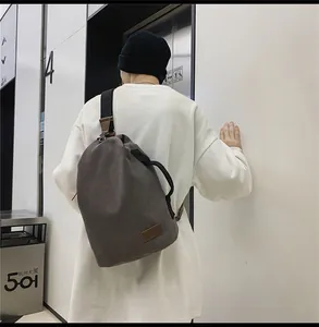 Dettaglio della borsa a tracolla in tela taupe scuro con ampia tracolla sulla modella