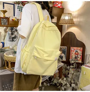 Detail of light yellow canvas backpack side pocket and cute bear logo on cream schoolbag
