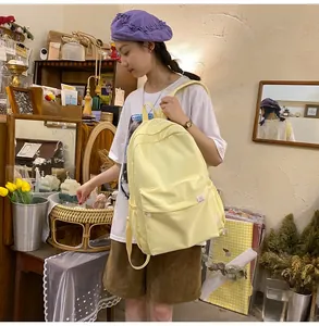 Close-up of a pale yellow canvas backpack with front zipper pocket and side water bottle holder