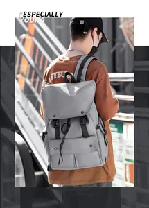 Detail view of light grey nylon backpack with flap closure and black buckle on city street