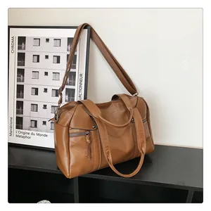 Detail of vintage brown leather tote bag showing smooth texture and tassel zipper pocket