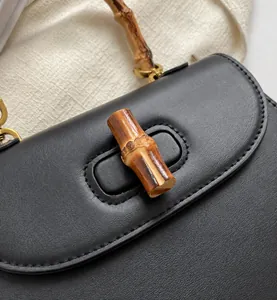 Détail d'un sac en cuir noir vintage avec poignée en bambou et fermoir doré chic