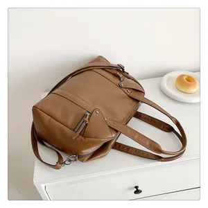Detail view of caramel brown faux leather handbag with retro zipper and stud accents