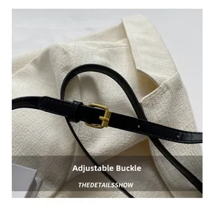 Détail de la bandoulière en cuir noir réglable avec boucle en métal doré de qualité