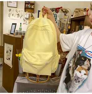 Close-up of yellow canvas backpack showing side brand tag and cute bear embroidery detail
