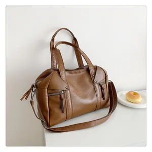 Detail of dark brown tote bag showing textured pebbled leather and tassel zippers