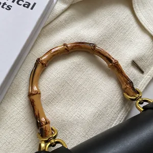 Détail du sac en cuir noir vintage avec poignée en bambou et finitions dorées