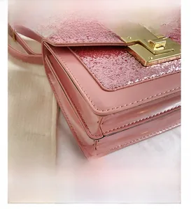 Detail presentation of pink sequin shoulder bag with golden metal push-lock and stitching