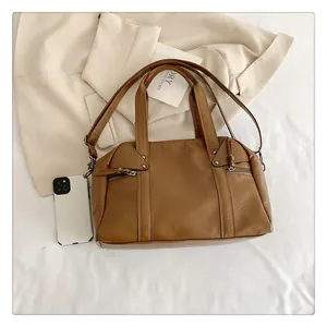Detailed close-up of brown leather handbag with metal zippers and studded triangle patch