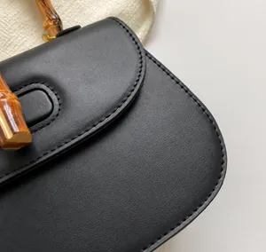 Détail d'un sac en cuir grainé noir avec poignée en bambou rétro et coutures précises