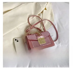Detailed view of pink glitter crossbody bag with marble lock next to a smartphone