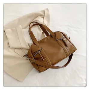 Detailed view of textured dark brown leather handbag with vintage bronze hardware