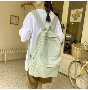 Outdoor view of a mint green minimalist backpack featuring large capacity and multi-pockets