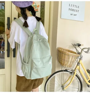 Detail view of a light green corduroy backpack with spacious pockets in a forest setting