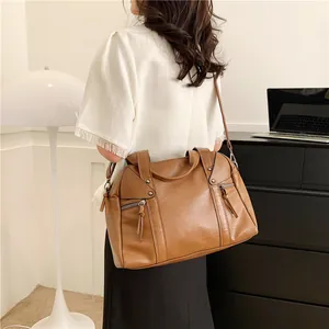 Brown leather tote bag with tassels and rivets worn by model for daily commute style