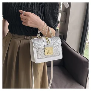 Detailed view of a white glitter shoulder bag with pearl handle and golden twist lock