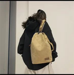 Borsa a secchiello in tela kaki con etichetta in pelle indossata a spalla