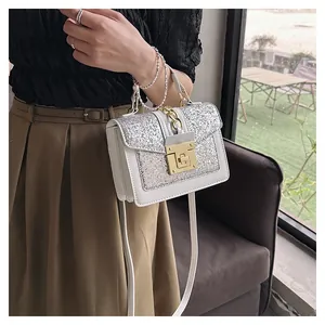 Detail of white leather crossbody bag with silver sequins and pearl chain handle
