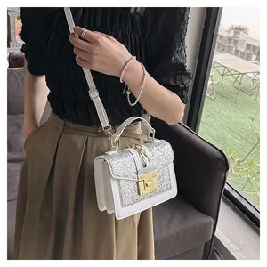 Close-up of white crossbody bag featuring silver glitter flap and gold metal lock detail