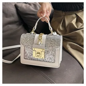 Detail of a beige crossbody bag featuring a silver glitter flap and metallic clasp