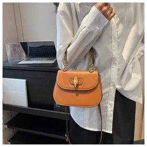 Détail d'un sac à main orange en cuir avec poignée en bambou et fermoir rotatif chic