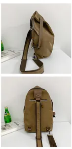 Detail view of khaki canvas crossbody bag with metal hooks and brown woven strap