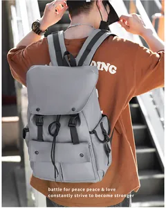 Detail of grey nylon backpack with drawstring closure and buckle straps on a male model