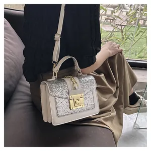 Close-up of a white sequined crossbody bag with gold chain handle and twist-lock closure
