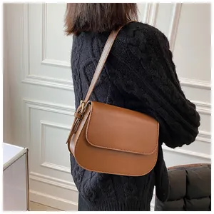 Caramel brown leather saddle bag with adjustable strap and gold buckle detail on model