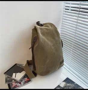 Dettaglio della borsa a tracolla in tela con chiusura roll-top e accenti in pelle marrone