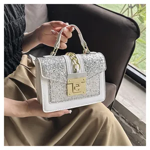 Detail of white sequin handbag with gold chain handle and metallic turn-lock closure