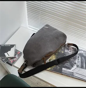 Dettaglio di una borsa a tracolla in tela grigia con tiranti della zip in pelle marrone