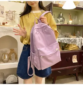 Detail of a purple minimalist canvas backpack with large front pocket and brand logo patch
