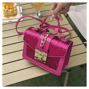 Detailed shot of sparkling hot pink glitter handbag with gold twist lock and metal chain