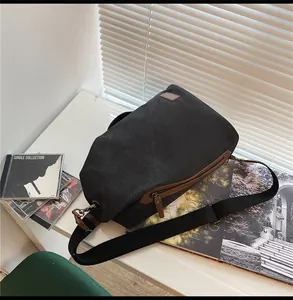 Dettaglio borsa a tracolla in tela nera con zip in pelle marrone e tracolla in nylon