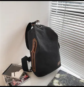 Dettaglio della borsa a tracolla in tela nera con accenti in pelle marrone e ganci metallici