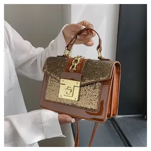 Close-up of brown sequined handbag with gold metal clasp and chain detail on leather