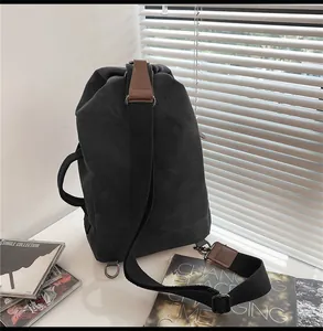 Dettaglio della borsa a tracolla in tela nera con finiture in pelle marrone e inserti in metallo